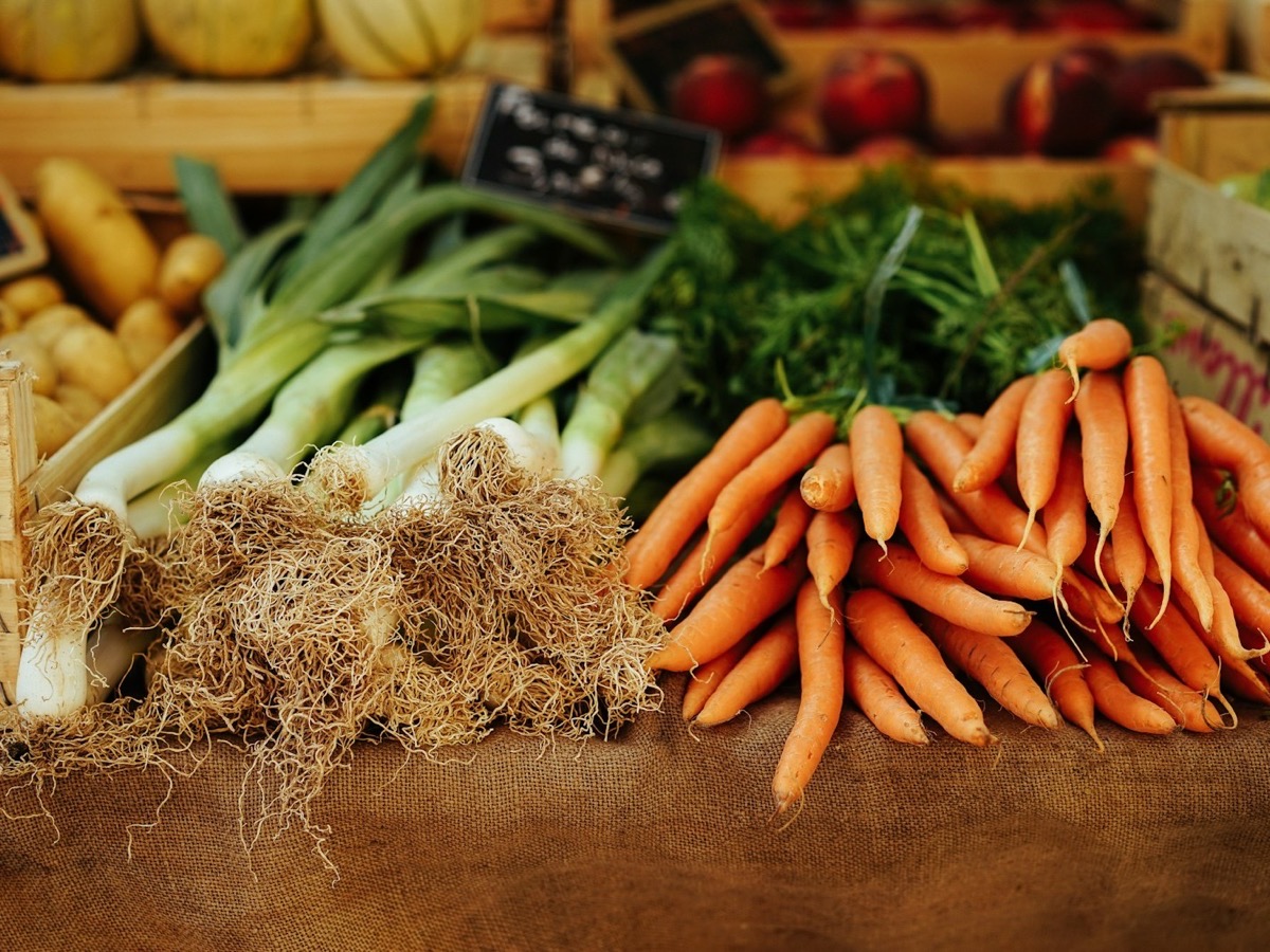 Freshly harvested carrots and leeks at a market stall